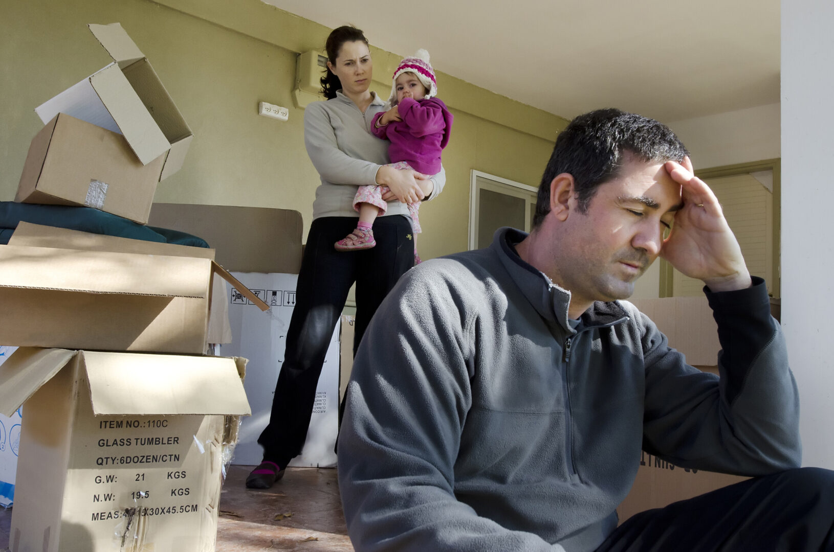 man in distress with woman and child in background and moving boxes around